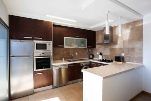 uma cozinha com armários de madeira e electrodomésticos de aço inoxidável em Apartamento SUNSET T3 em São Martinho do Porto