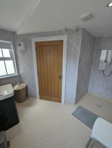 a bathroom with a wooden door and a sink at Derg Valley Apartments in Castlederg