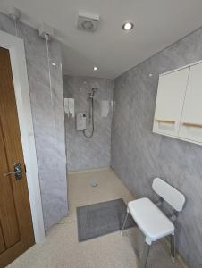 a bathroom with a shower with a chair and a stool at Derg Valley Apartments in Castlederg
