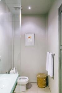 Lovinalife Room & Cafe في لوفينا: حمام ابيض مع مرحاض ومغسلة