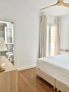 a white bedroom with a bed and a mirror at Ático con Vistas in Vélez Rubio