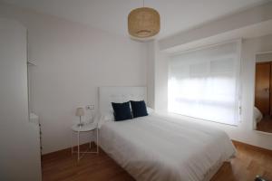 una camera da letto con un letto bianco con cuscini blu e una finestra di Adosinda Suite a Gijón