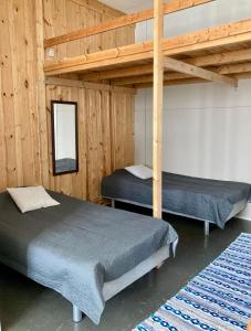 two beds in a room with wooden walls at Kotapiha in Liperi