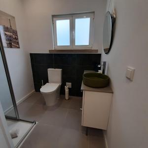 uma casa de banho com um WC, um lavatório e uma janela em Casa da Esquina - Sintra em Sintra