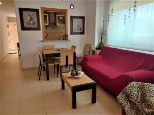ein Wohnzimmer mit einem roten Sofa und einem Tisch in der Unterkunft APCOSTAS Aguamarina - Valparaiso in Oropesa del Mar
