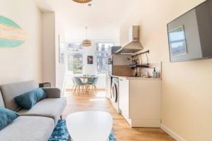a living room with a couch and a kitchen at Suite Californienne - Hyper Centre 5min Gare in Valenciennes