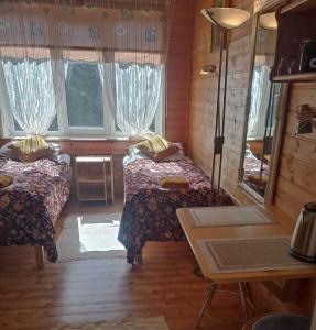 Cette chambre comprend 2 lits, une table et un miroir. dans l'établissement Vingi Apartment 12, à Pärnu