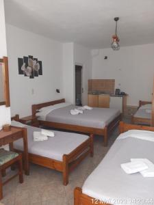 ein Hotelzimmer mit 3 Betten und einer Küche in der Unterkunft Happy Days in Agia Galini