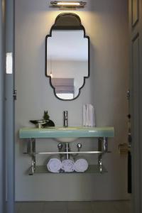 W łazience znajduje się umywalka z lustrem i ręczniki. w obiekcie Lovinalife Room & Cafe w mieście Lovina