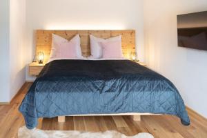 a bedroom with a large blue bed with pink pillows at Going Living in Going am Wilden Kaiser