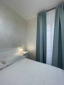 a bedroom with a bed and a window with blue curtains at La casa in centro in Salerno