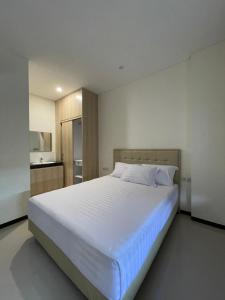 a bedroom with a large white bed and a kitchen at Kawa Living in Krukah