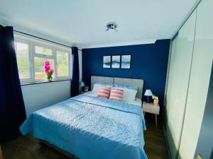 1 dormitorio con paredes azules y 1 cama con almohadas rosas en Cloud9StayZ at The Leafield, en Woking