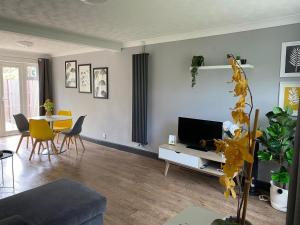 a living room with a television and a table and chairs at Cloud9StayZ at The Leafield in Woking