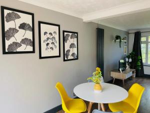 a dining room with a white table and yellow chairs at Cloud9StayZ at The Leafield in Woking