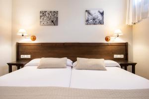 1 dormitorio con 1 cama blanca grande y 2 almohadas en Apartamentos Aldea del Puente, en Cangas de Onís