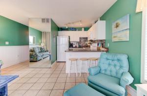 uma cozinha e sala de estar com paredes verdes e cadeiras azuis em 0701 The Green Starfish by Atlantic Towers em Carolina Beach