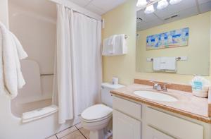 Un baño con inodoro, lavabo y espejo. en 0701 The Green Starfish by Atlantic Towers, en Carolina Beach