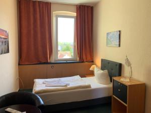 a small bedroom with a bed with a window at Pension zur Ostsee in Kölpinsee