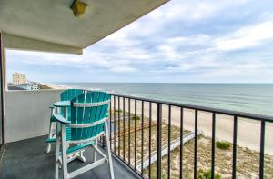 una mecedora azul sentada en un balcón con vistas a la playa en 0701 The Green Starfish by Atlantic Towers, en Carolina Beach