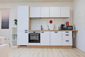a white kitchen with white cabinets and appliances at Klassen Apartments! Erleben Sie Aulendorf in dieser modernen Unterkunft in Aulendorf