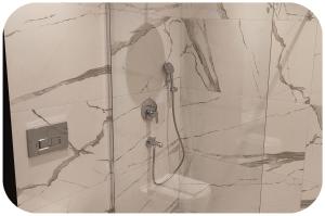La salle de bains est pourvue d'une douche et d'un mur en marbre. dans l'établissement Aslan Residence, à Istanbul