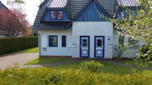a white house with blue doors and a yard at Mensendiek, Anita, App in Zingst