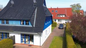 a house with a black roof and a car on a street at Mensendiek, Anita, App in Zingst
