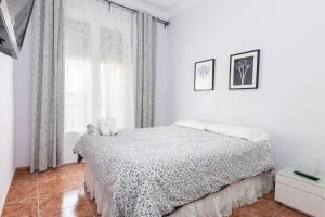 a white bedroom with a bed and a window at ApartEasy - Modernist flat in Eixample center in Barcelona