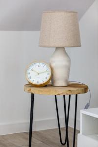 a table with a lamp and a clock on it at Resort Kropli Bałtyku Apartments by Renters in Darłowo