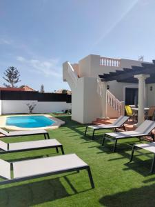 un patio trasero con tumbonas y piscina en Ereza Villa Paraiso en La Oliva