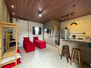a living room with red chairs and a kitchen at Loft Menezes Olinda in Olinda