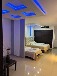 duas camas num quarto com luzes azuis no tecto em Aparta Hotel El Cacique Upar em Valledupar