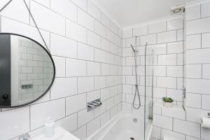 a white bathroom with a tub and a mirror at Just-renovated flat in the centre of Shoreditch! in London
