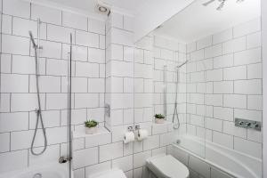 a white tiled bathroom with a toilet and a shower at Just-renovated flat in the centre of Shoreditch! in London