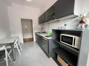 a kitchen with black cabinets and a microwave and a table at Mickitos Square Apartment in Skopje