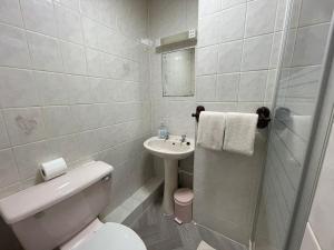 a white bathroom with a toilet and a sink at Galaxy Hotel in Blackpool