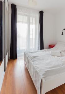 a white bed in a room with a large window at Dobó Apartman in Szeged