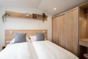 1 Schlafzimmer mit 2 weißen Betten und Holzschränken in der Unterkunft Ostseecamp Ferienhaus "StrandPerle" in Scharbeutz