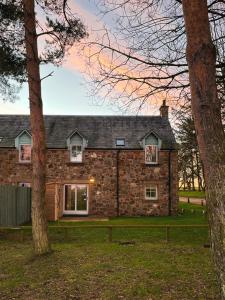 una casa de piedra con árboles delante de ella en At The Bay en St Andrews