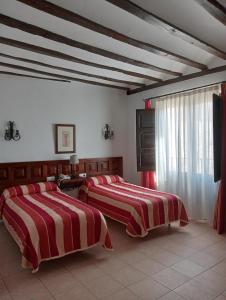 two beds in a bedroom with red and white blankets at Hotel Nuevo Arlanza in Covarrubias