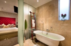 een badkamer met een bad en een slaapkamer met een bed bij Grand Daddy Boutique Hotel in Kaapstad