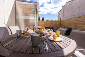 a wooden table with food and drinks on a patio at Maison classée 3étoiles proche plage in Mauguio