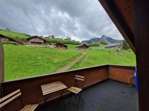 a balcony with two chairs and a view of a field at Sanner Valley Home in Boltigen