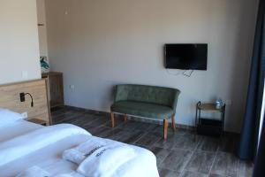 1 dormitorio con 2 camas, silla y TV en Mavriya en Geyikli