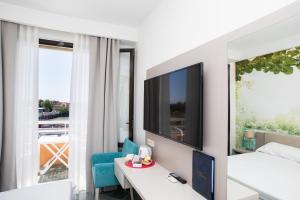 Habitación de hotel con cama, escritorio y TV. en Hotel L'Approdo en Castiglione della Pescaia