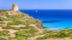 un faro en la cima de una colina cerca del océano en Hotel Solki, en SantʼAntìoco