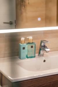 umywalkę w łazience z 2 butelkami mydła i lustrem w obiekcie Modern beach apartment Romana Playa 723 in Marbella, Elviria w Marbelli