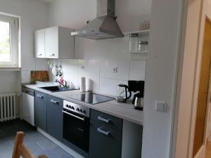 eine Küche mit weißen Schränken und einem schwarzen Herd mit Backofen in der Unterkunft Helle 3 Zimmer Wohnung in Krefeld