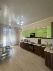 una cocina con armarios verdes, mesa y sillas en 1 bedroom Seaside apartments in Green Park 1 комнатная квартира en Aktau